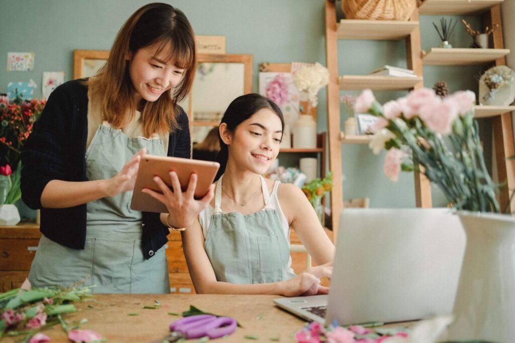 two women using digital devices and setting up their own online floral business